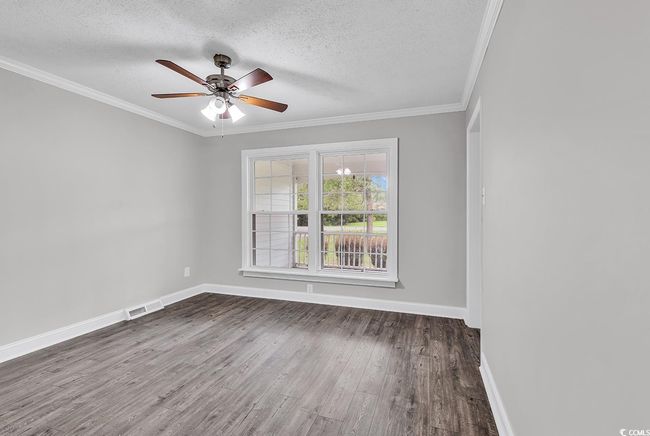Spare room with wood finished floors, a textured ceiling, crown molding, and ceiling fan | Image 8