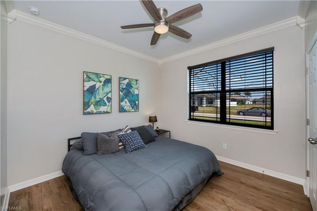 Bedroom with crown molding, a ceiling fan, baseboards, and wood finished floors | Image 19