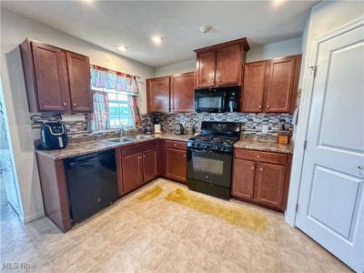 Kitchen featuring black appliances, backsplash, sink, a window, and a pantry | Image 2