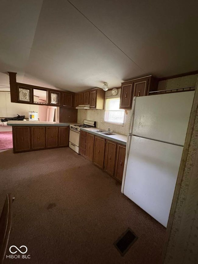 kitchen with white appliances, carpet flooring, lofted ceiling, and light countertops | Image 11