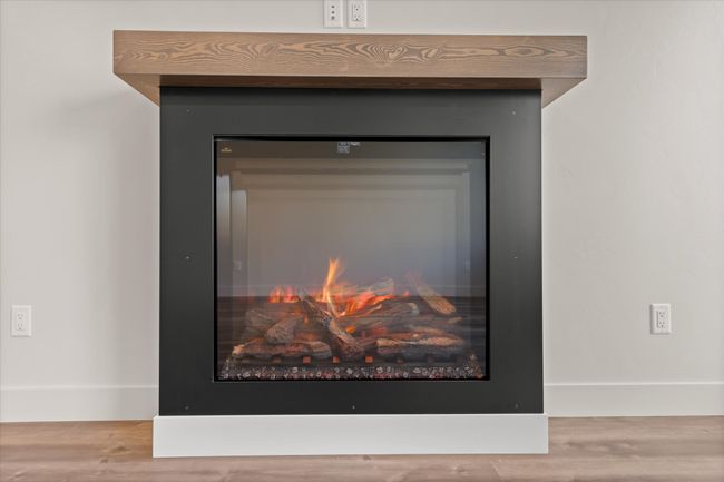 Room details featuring a glass covered fireplace and wood finished floors | Image 13