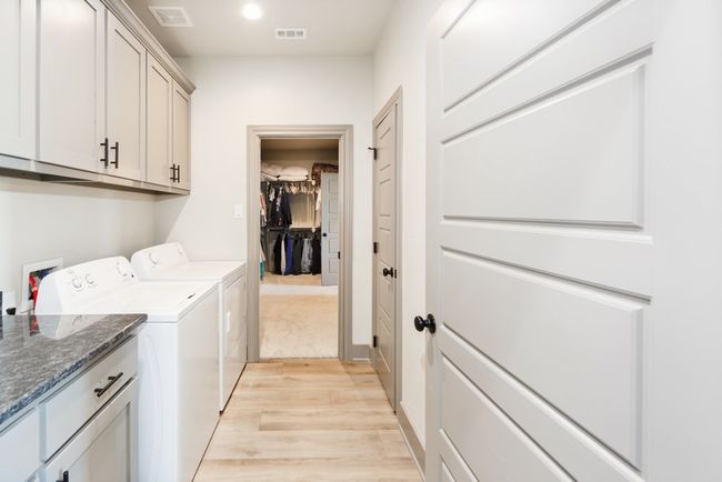 Clothes washing area featuring visible vents, washer and clothes dryer, cabinet space, and light wood-type flooring | Image 21
