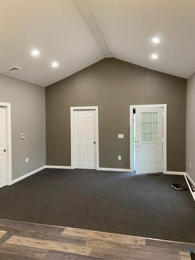 Carpeted spare room featuring vaulted ceiling | Image 13