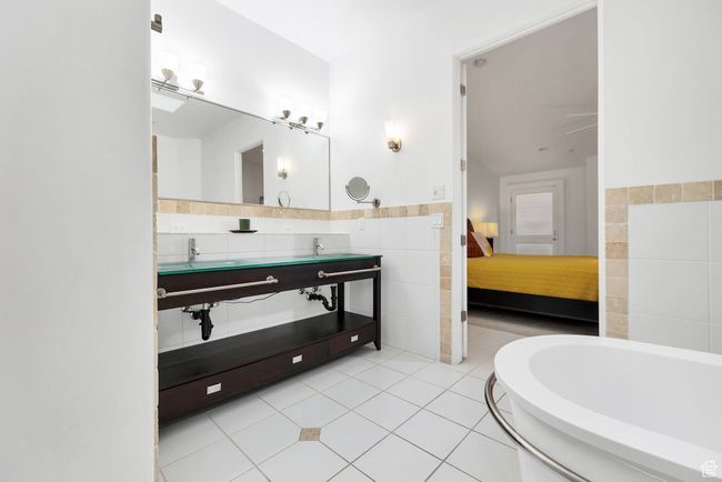 Bathroom featuring tile patterned flooring, a wainscoted wall, tile walls, ensuite bath, and a bathtub | Image 13
