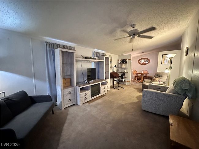 Living room with a textured ceiling, a ceiling fan, and carpet | Image 9