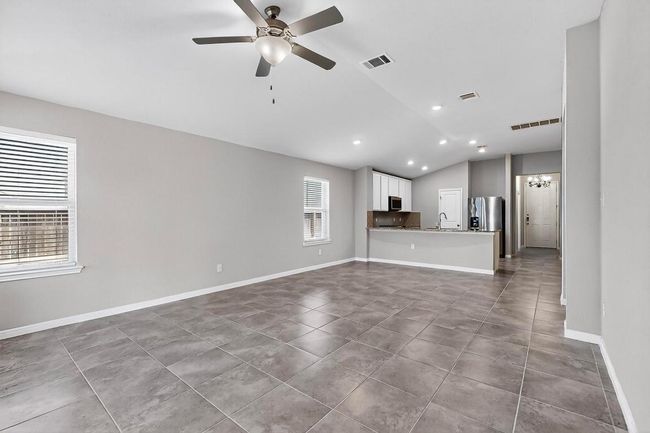 Unfurnished living room with vaulted ceiling, a ceiling fan, recessed lighting, and tile patterned floors | Image 10