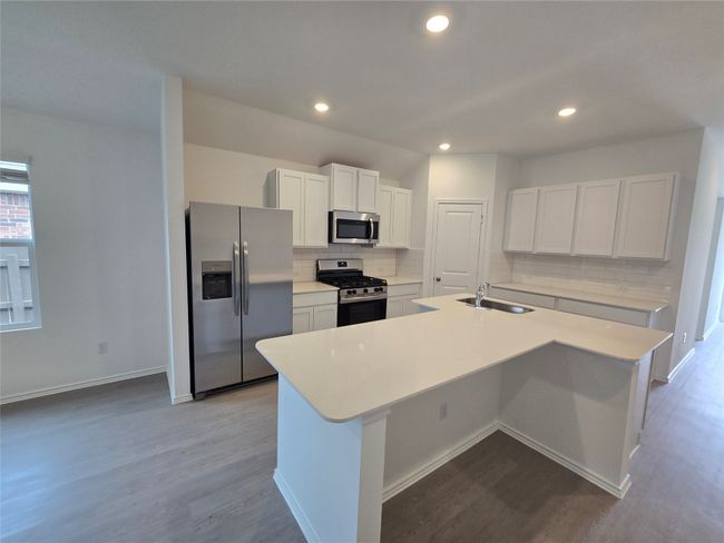 Kitchen with appliances with stainless steel finishes, dark wood finished floors, backsplash, a kitchen island with sink, and recessed lighting | Image 9