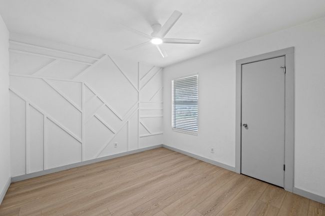 Unfurnished view of bedroom with custom wall, ceiling fan, and walk-in closet | Image 14