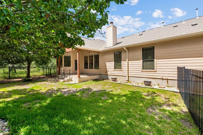 Rear view of house featuring a patio, a chimney, a fenced backyard, and roof with shingles | Image 32