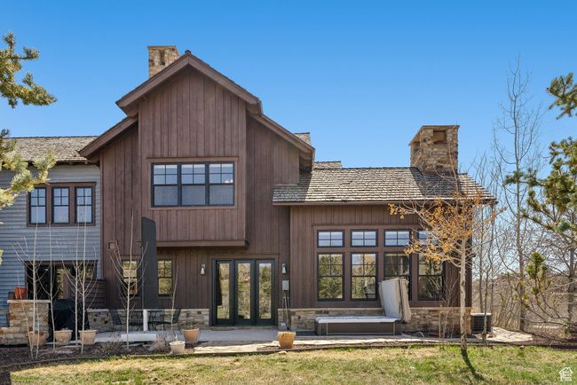 Rear view of property featuring french doors, central AC, a chimney, and stone siding | Image 37