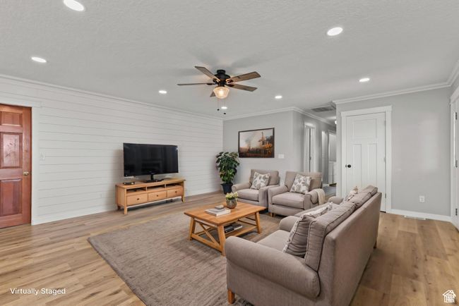 Living room featuring ornamental molding, ceiling fan, recessed lighting, light wood-style flooring, and wood walls | Image 12