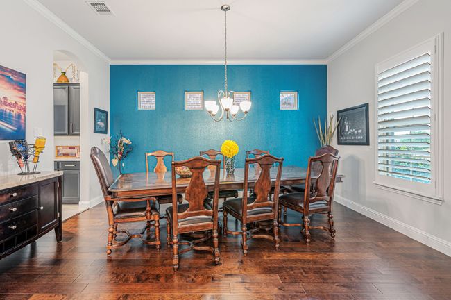 Dining area featuring ornamental molding, an accent wall, and chandelier | Image 6
