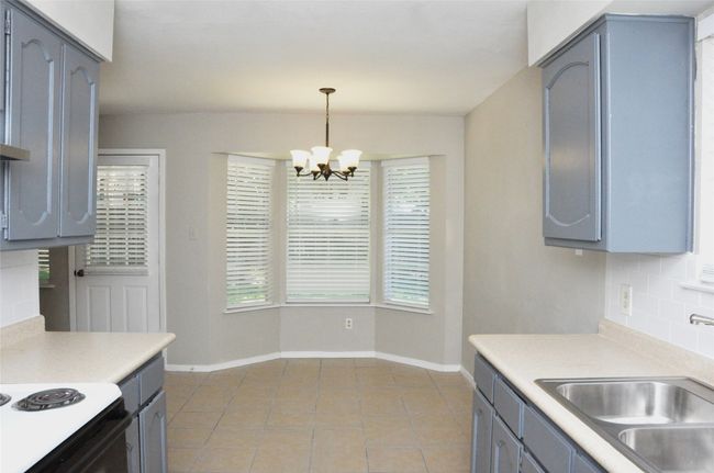Kitchen with gray cabinets, decorative backsplash, and a sink | Image 15