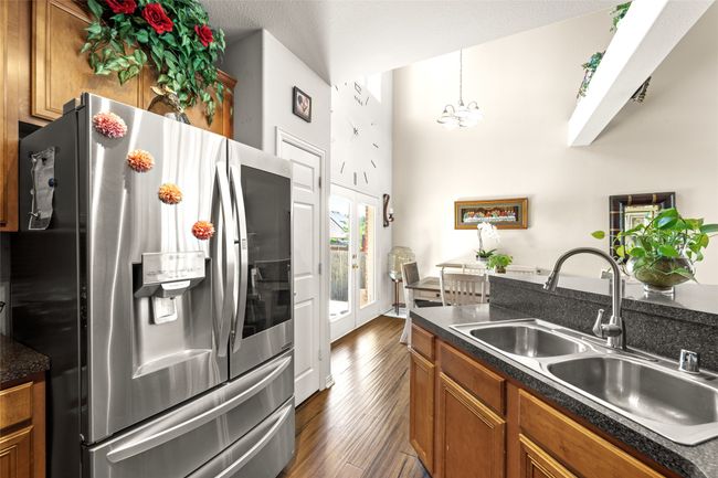 Kitchen with stainless steel applances with dual sink, brown cabinetry, dark wood finished floors, and dark countertops | Image 12