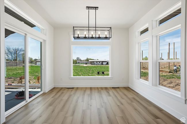 Unfurnished dining area featuring plenty of natural light, a notable chandelier, baseboards, and light wood-style flooring | Image 8