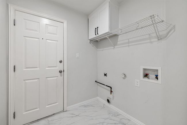 Washroom with gas dryer hookup, cabinet space, light marble finish floors, hookup for an electric dryer, and hookup for a washing machine | Image 30