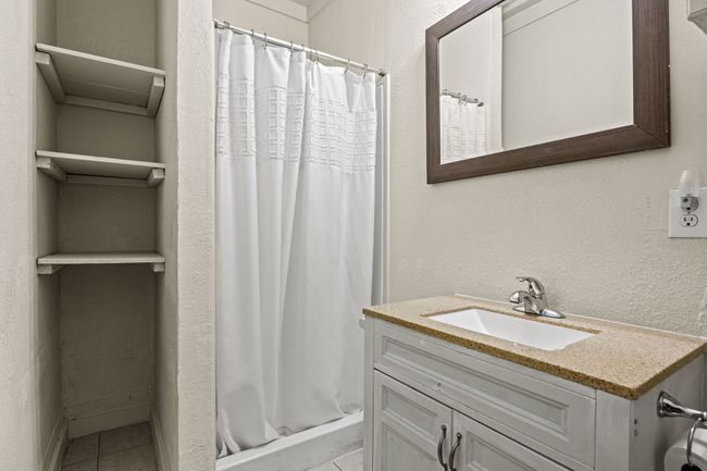 Full bathroom featuring a shower with curtain, tile patterned flooring, a textured wall, and vanity | Image 15