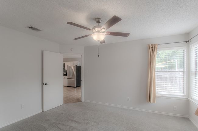 Empty room with light carpet, a textured ceiling, and a ceiling fan | Image 16