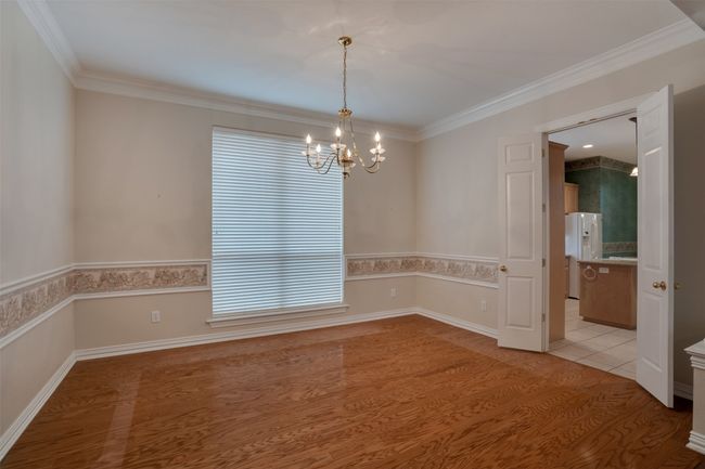 Unfurnished room featuring a chandelier, crown molding, light wood-style flooring, and baseboards | Image 8