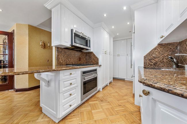 Kitchen featuring stainless steel appliances, white cabinetry, recessed lighting, dark stone countertops, and backsplash | Image 11