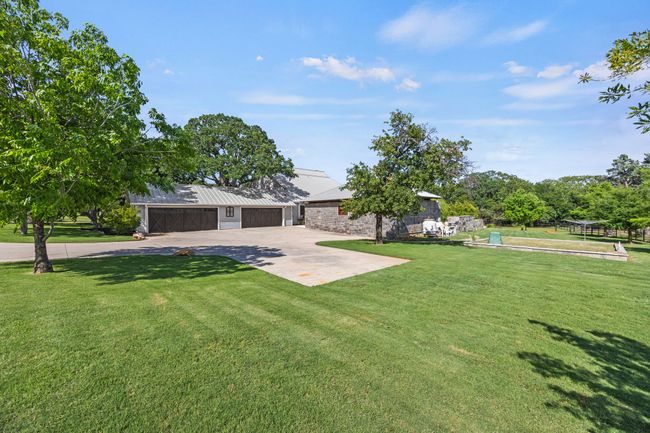 View of 4 Car Garage with Cedar Doors, Driveway, Garden Bed, Outdoor Living Center | Image 34