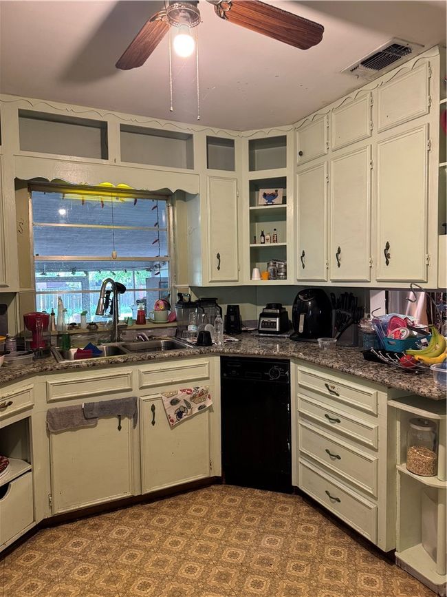 Kitchen with open shelves, a sink, dishwashing machine, a ceiling fan, and white cabinets | Image 6