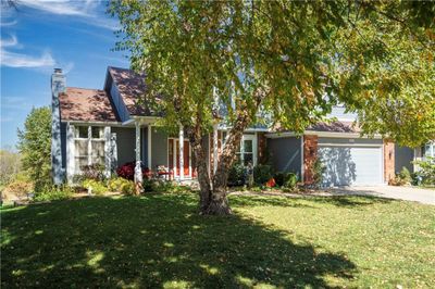 View of property hidden behind natural elements featuring a garage and a front lawn | Image 3