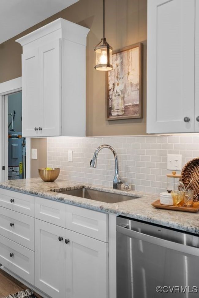 Kitchen featuring stainless steel dishwasher, white cabinets, a sink, and decorative backsplash | Image 11