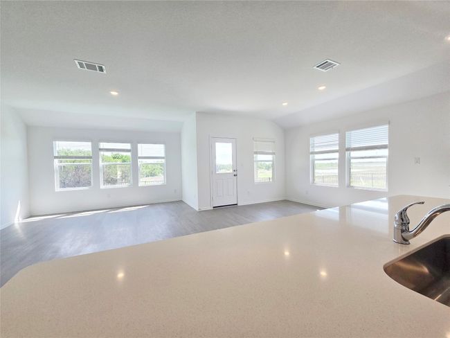 Unfurnished living room featuring a sink, plenty of natural light, wood finished floors, recessed lighting, and baseboards | Image 11