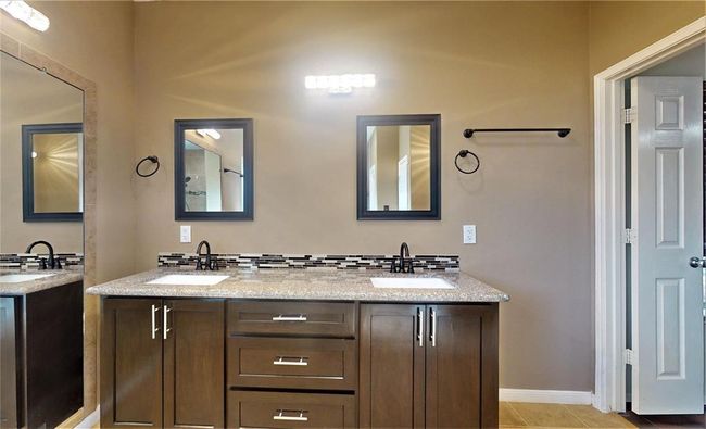 Elegant primary bathroom featuring a sleek double vanity, modern fixtures, and ample storage. | Image 24