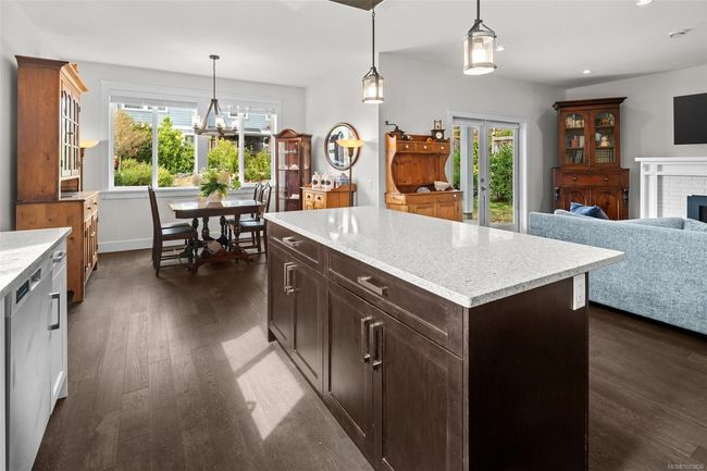 Kitchen with dark wood-type flooring, stainless steel dishwasher, hanging light fixtures, recessed lighting, and a fireplace | Image 19