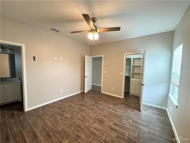 Unfurnished bedroom featuring a sink, dark wood-type flooring, baseboards, and a walk in closet | Image 11