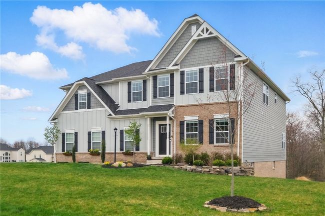 Gorgeous two-story home with a striking mix of brick and board-and-batten siding, black shutters, and detailed trim work. Set on a spacious lot with a paved driveway, two-car garage, and professionally landscaped yard, all backing to a wooded backdrop for added privacy. | Image 37