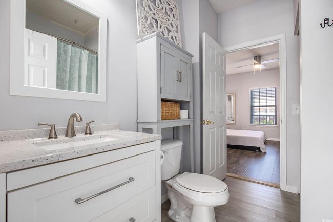 Bathroom featuring wood finished floors, vanity, toilet, a ceiling fan, and baseboards | Image 15