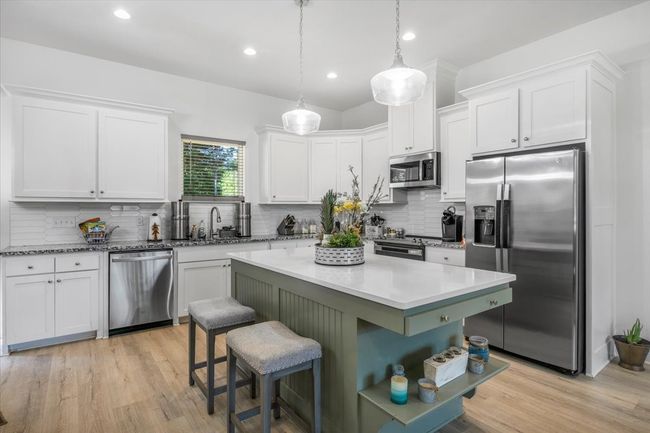 Kitchen with backsplash, a sink, white cabinetry, and stainless steel appliances | Image 12
