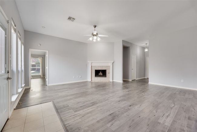 Unfurnished living room featuring ceiling fan, light wood-style floors, a fireplace, and baseboards | Image 5