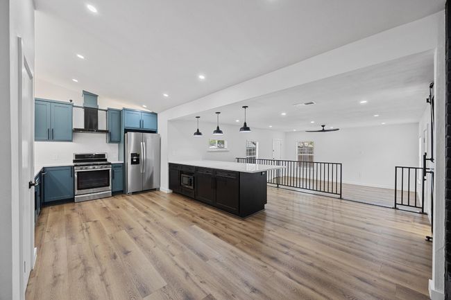 Kitchen with appliances with stainless steel finishes, wall chimney exhaust hood, a peninsula, light countertops, and recessed lighting | Image 7