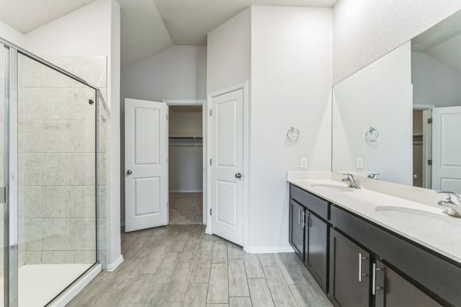 Bathroom featuring lofted ceiling, a spacious closet, double vanity, a stall shower, and wood finished floors | Image 7