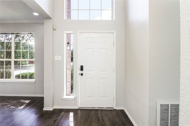 Entrance foyer featuring dark wood-style floors, baseboards, ornamental molding, a textured wall, and recessed lighting | Image 4