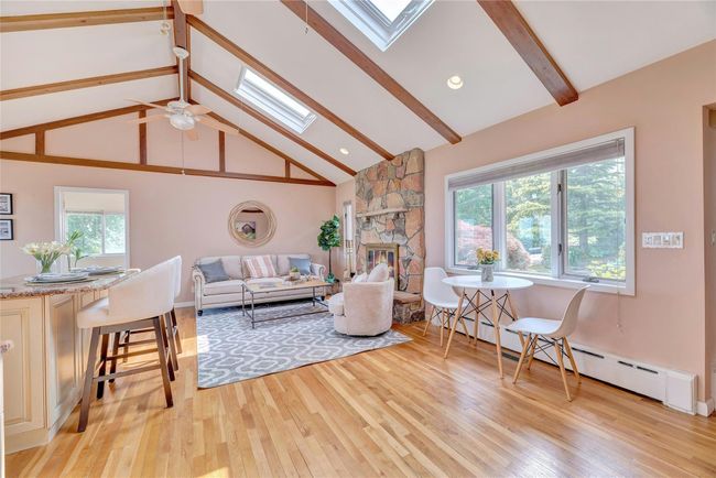 Living room featuring a skylight, light wood-type flooring, and high vaulted ceiling | Image 9