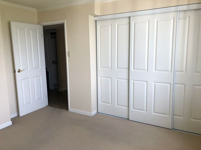 Unfurnished bedroom featuring crown molding, baseboards, a closet, and light carpet | Image 24