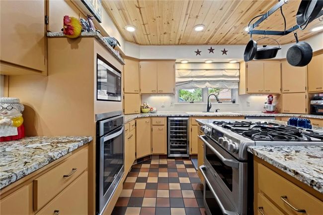 Kitchen featuring stainless steel appliances, beverage cooler, wood ceiling, recessed lighting, and dark flooring | Image 10