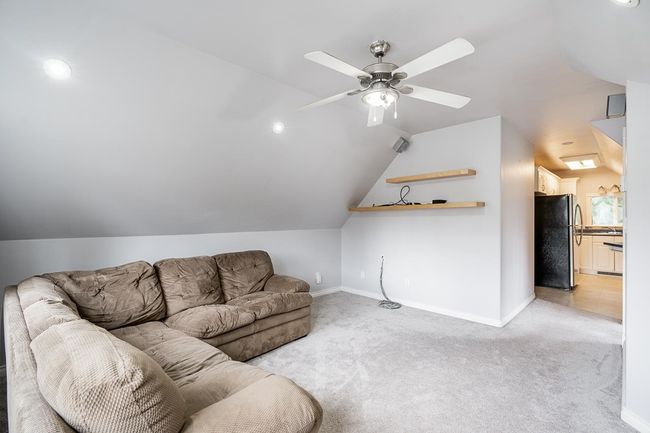Living room with baseboards, vaulted ceiling, a ceiling fan, and light carpet | Image 28
