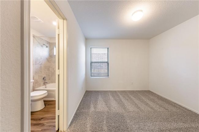 Unfurnished bedroom featuring connected bathroom, a textured ceiling, and carpet floors | Image 11
