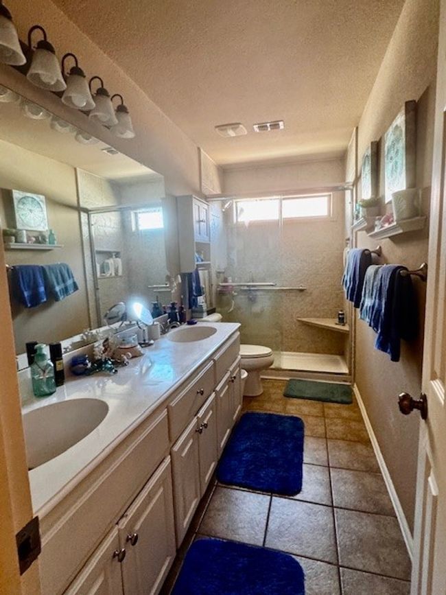 Bathroom featuring a wealth of natural light, a shower stall, a textured ceiling, toilet, and a sink | Image 15
