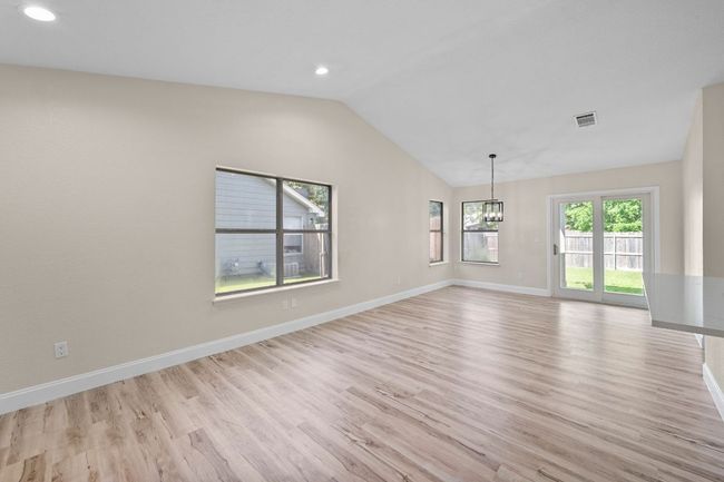 Empty room with lofted ceiling, a chandelier, light wood-style floors, and recessed lighting | Image 5