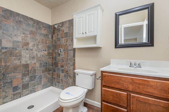 Full bathroom featuring a textured wall, vanity, a stall shower, and dark wood-style floors | Image 18