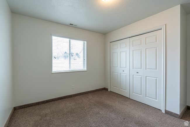 Unfurnished bedroom featuring a closet, a textured ceiling, visible vents, carpet, and baseboards | Image 13