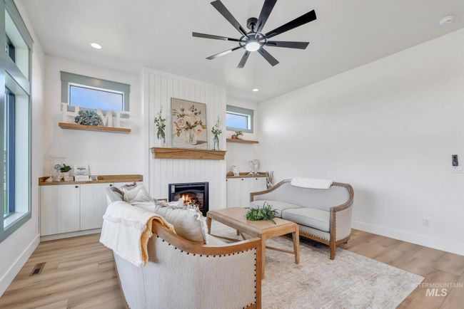 Living room with a fireplace, a ceiling fan, light wood-type flooring, and recessed lighting | Image 5
