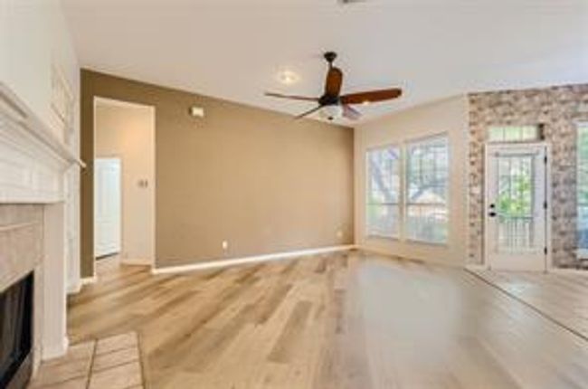 Unfurnished living room featuring a fireplace, ceiling fan, and wood finished floors | Image 17